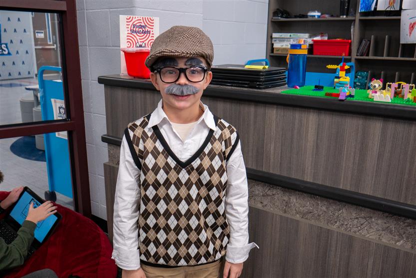 boy in sweater vest and hat in the library